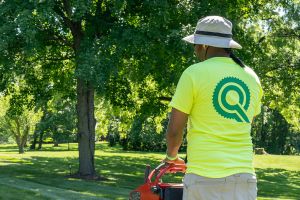 Team Quality Care lawn health care employee in hat and branded apparel 