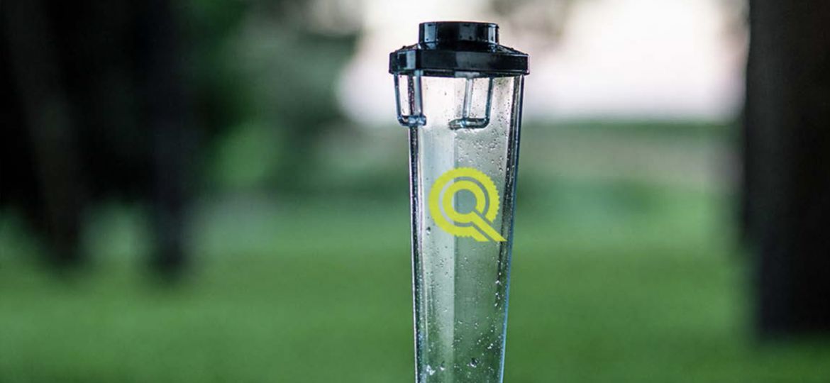Quality Care logo on rain gauge in lush green grass cropped