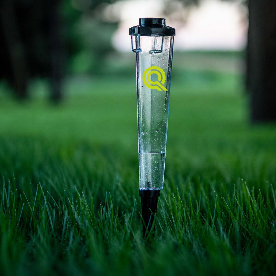 Quality Care logo on rain gauge in lush green grass